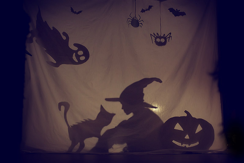 Shadow of kid with witch hat and other halloween paraphernalia 