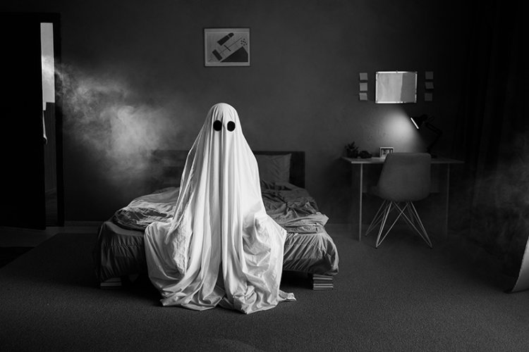 Ghost sitting on a bed in a smoke room