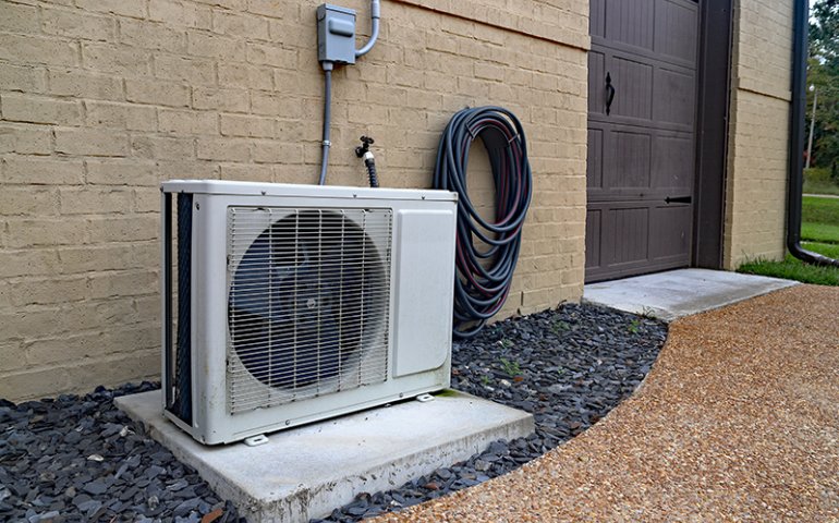 Mini split system next to home with a brick wall